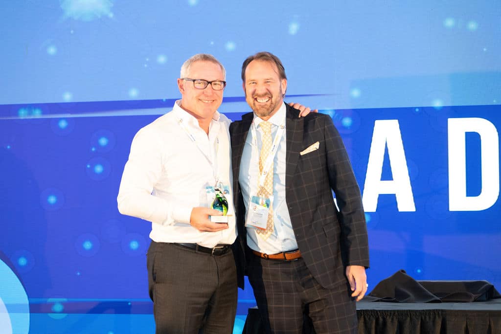 Two delegates on stage with an industry award
